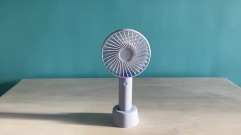 Front view of a compact desktop mini fan spinning steadily on a table again.. Stock Footage 331791075