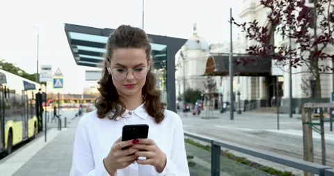 Front view of confident young lady in eyewear and white shirt walking on street  Stock-Footage 136174242