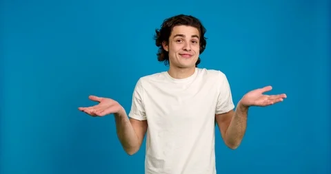 Front view of confused young man showing shrug gesture isolated on blue Stock Footage 123967672
