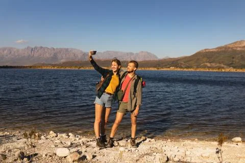 Front view of couple taking selfies in front of a lake Stock Photos