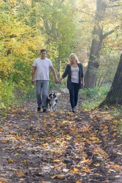 Front view of a couple walking through an autumn park Stock Photos