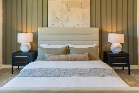Front view of cozy bed with beige duvet, green pillows and lamp, with copy space Stock Photos