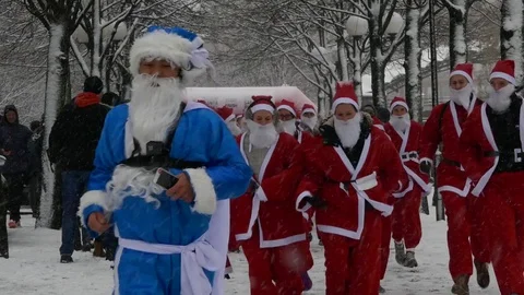 Front view crowd of Santa Clauses running in street heavy snow, new year charity Stock Footage 70645857