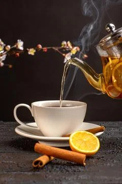 Front view cup of tea with lemon cinnamon and kettle on grey desk tea drink.. Фото