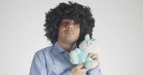 Front view of a curly-haired embracing and cuddling his plush bunny Stock Footage 147469866