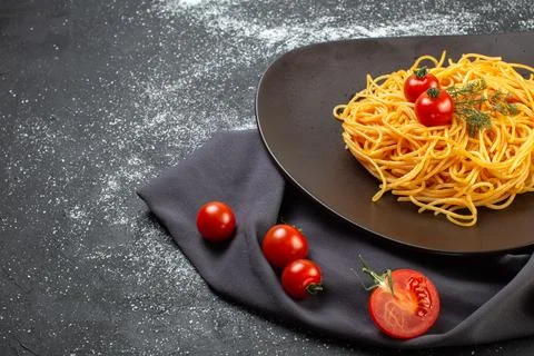 Front view of delicious spagetti on a black plate on a dark color towel raw.. Stock Photos