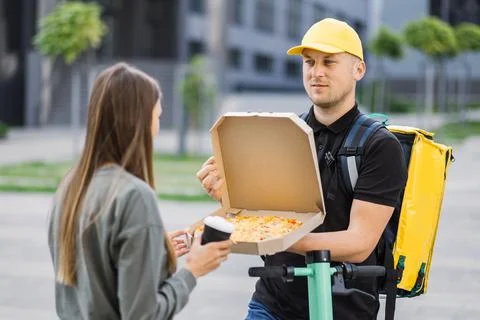 Front view of a delivery man coming to the building of customer and meet young Stock Photos