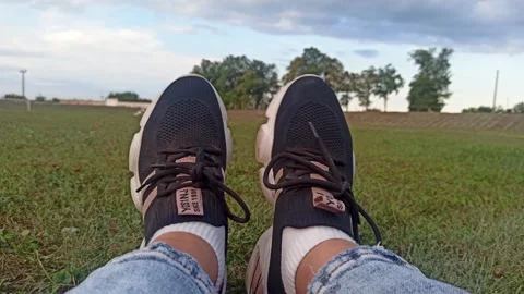 Front view dirty old sneakers moving  , girl's feet sitting on football field,ho Stock Footage 249694030