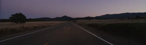 Front view of a Driving Plate: Car travels at dusk past farms and fields on Stock Footage 59330482