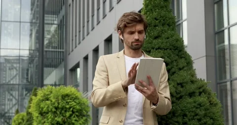Front view of emotional bearded man using digital tablet outdoors. Handsome Stock Footage 137744447
