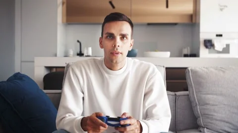 Front view of excited caucasian guy playing video game and using joystick Stock Footage 138905030