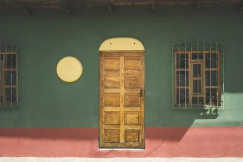 Front view of the facade of the colorful wall house with wooden doors and win Stock Photos