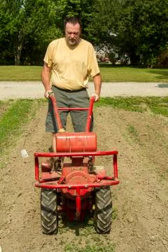 Front View Of Farmer Using A Garden Tiller Stock Photos
