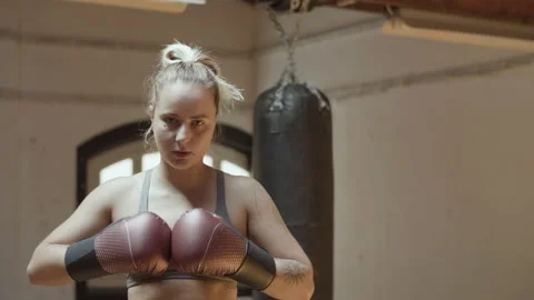 Front view of female boxer in boxing gloves standing in gym Stock Footage 166088086