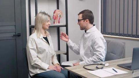 Front view of a female patient being fitted with a hearing aid by a doctor Stock Footage 248352348