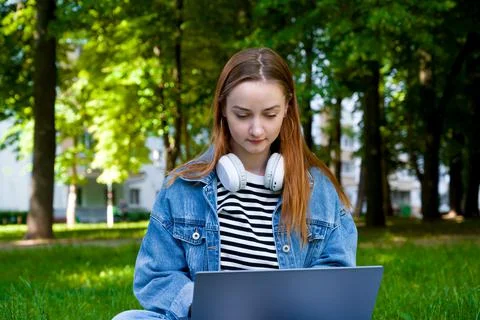 Front view on female using laptop for work or education in the parl.Remote ed Stock Photos