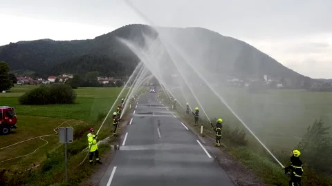 Front view of fire truck coming through ceremonial water arch with firefighters Stock Footage 323793767