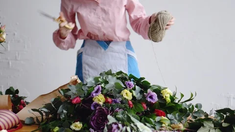 Front view of florist cuts a thread with scissors to arrange a bouquet Stock Footage 86769731