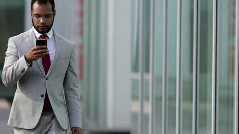 Front view of focused businessman using smartphone during stroll Video stock 114963280