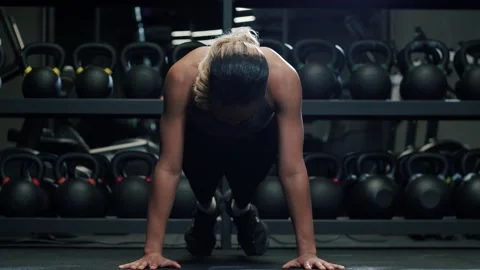 Front view of focused young African woman doing push-ups in gym in background of Stock Footage 189013465