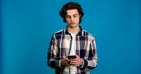 Front view of focused young man typing on smartphone and smiling isolated on Stock Footage 124535241