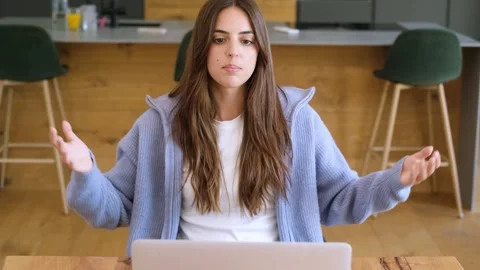 Front view of a focused young woman sitting at her desk, talking and gesturing Stock Footage 346870539