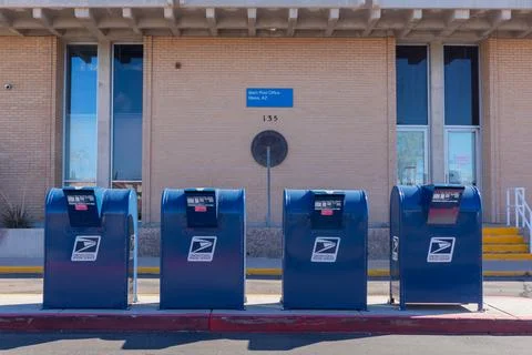 Front view of four blue USPS mailboxes in front of post office Stock Photos
