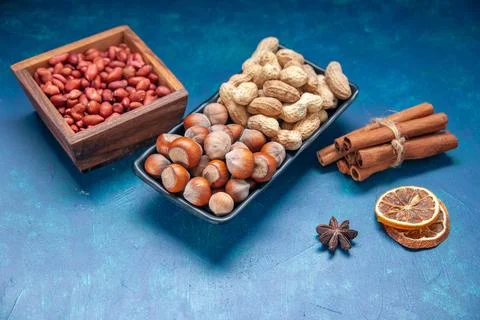 Front view fresh nuts cinnamon peanuts and hazelnuts on blue background col.. Stock Photos
