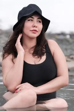 Front view of full figured young adult model in black one piece bathing swims Stock Photos
