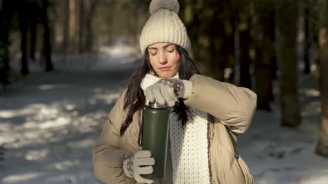 Front view. The girl opens a thermos with tea in a snowy forest Stock Footage 154205701