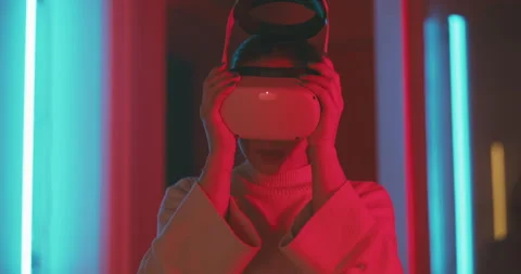 Front view of a girl trying on vr glasses in pink and blue neon light Stock Footage 201110042