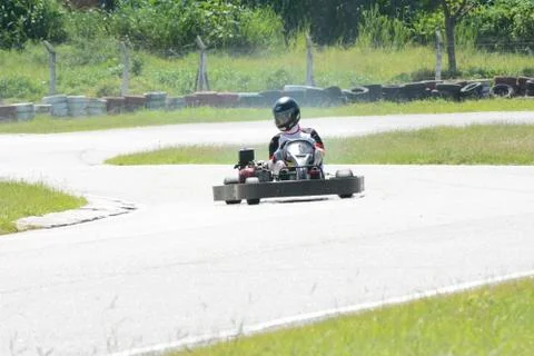 Front view of go-kart driver driving on race track on sunny day Stock Photos