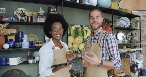 Front view of good-looking in high spirits friendly mixed race sellers in aprons Stock Footage 143966895