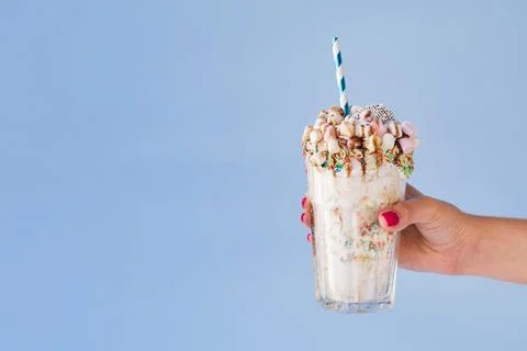 Front view hand holding milkshake with blue background. High quality beauti.. Stock Photos