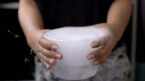 Front view of hands holding container of cryogenic gas with white smoke Stock Footage 119071493