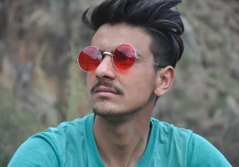 Front view of a handsome Indian guy wearing sunglass while sitting outdoor Stock Photos