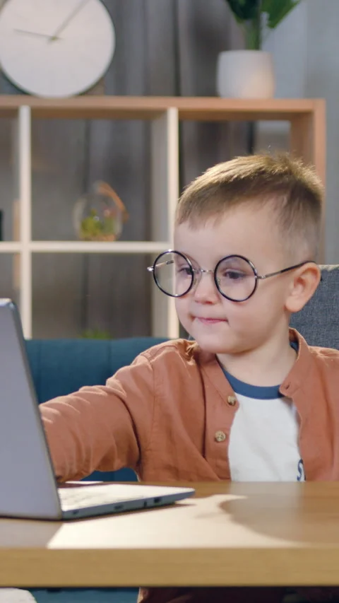 Front view of handsome small interested kid in round eyeglasses which sitting in Stock Footage 328843049