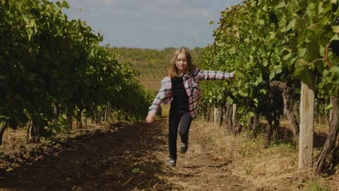 Front view of a happy little girl running through rows of vines Stock Footage 162835053