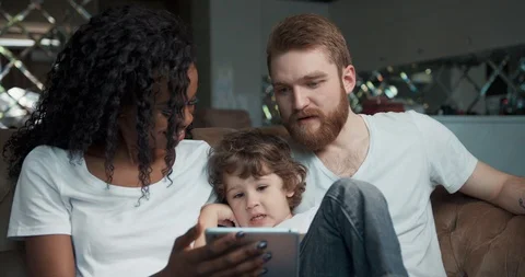 Front view of a happy mixed race couple sitting on a sofa having a good time Stock Footage 123214426