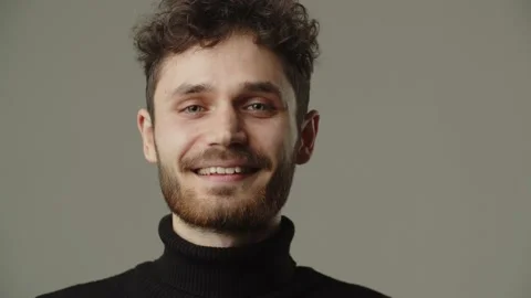 Front view of a happy young man. A man with curly hair smiles while looking at Stock Footage 237031827