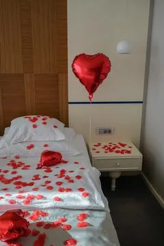 Front View of Heart Balloon Floating Above Romantic Decorated Bed Foto stock