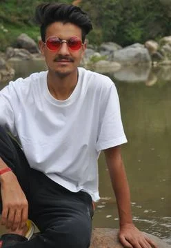 Front view of a Indian young guy sitting on stone in river Foto stock