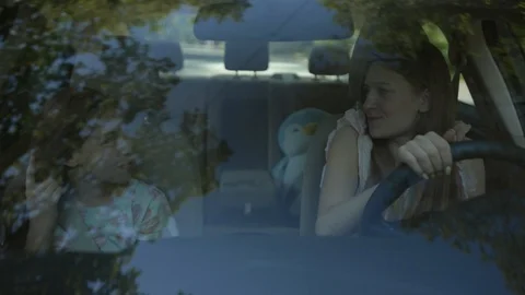 Front view inside the car of two girls sisters having fun dancing into music Video stock 112749097