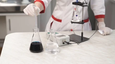 A front view of the lab technician filling a pipette with blue chemical Stock Footage 108859264