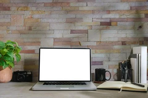 Front view of laptop with blank screen, coffee cup, notebook and houseplant.. Stock Photos