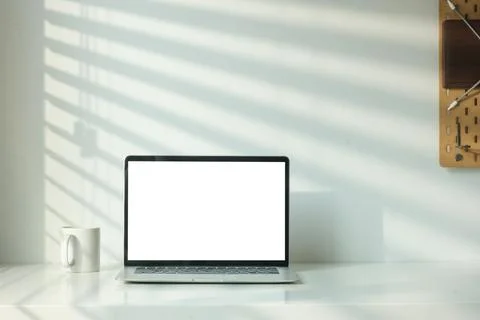 Front view of laptop computer and coffee cup on table with shadow from the .. 写真素材