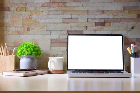 Front view of laptop computer, coffee cup, potted plant and stationery on c.. Stock-Fotos