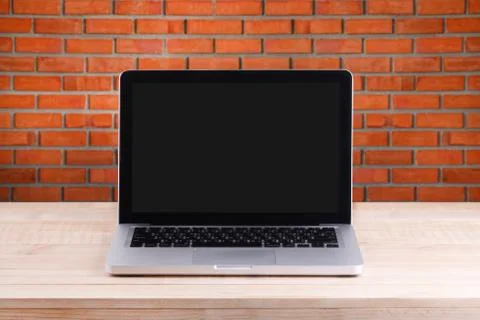 Front view of the laptop is on the work table brick background Stock Photos