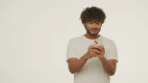 Front view of laughing Indian man texting message. Studio footage of a Stock Footage 231902047