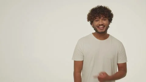 Front view of laughing young man pointing with finger to the side. Curly guy Stock Footage 232803961
